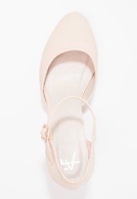 Beżowy but na wysokim obcasie z teksturowaną cholewką, zwężającym się czubkiem i bocznym paskiem z klamrą. Gładka podszewka wewnętrzna. Podeszwa ma delikatny połysk.