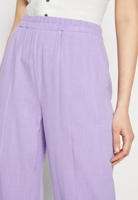 Helle lila, locker sitzende Hose aus strukturiertem Stoff. Elastischer Bund mit vorderen Falten, mit einem sanften, fallenden Design.