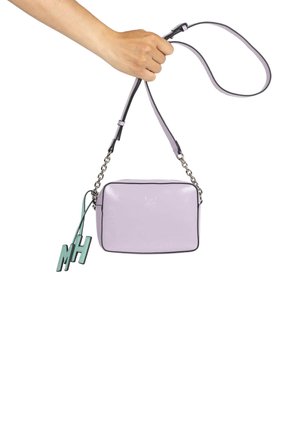 Bolso cruzado de cuero lila con forma rectangular, ribetes negros, correa de cadena plateada y una etiqueta de color azul verdoso con "MH" adjunta.