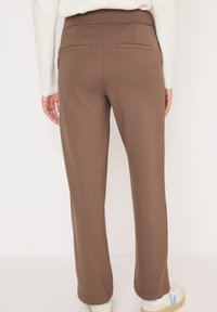 Bruine stretchstof broek met een platte tailleband, rechte pijpen en twee achterzakken. Glad textuur en casual pasvorm.