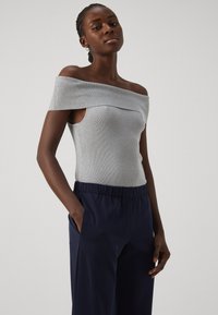 Geribd, grijs topje met blote schouders en een aansluitend ontwerp, gecombineerd met marineblauwe broek met een elastische tailleband en zijzakken.