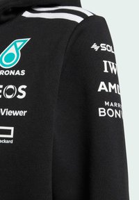 Sudadera negra con acentos blancos y múltiples logotipos de patrocinadores en blanco. Textura suave, diseño casual, con capucha ajustable.