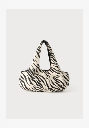 Borsa di stoffa a righe bianco e nero stile zebra con base ampia e curva e una singola maniglia che forma un anello aperto superiore.