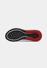 Suola di scarpa da ginnastica nera e rossa con un motivo di grip testurizzato. Presenta un bordo bianco liscio e un dettaglio del logo nella sezione rossa.
