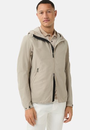 Lightweight beige jacket with a hood, zip closure, two side pockets, and black accents on the collar; smooth, water-resistant fabric.