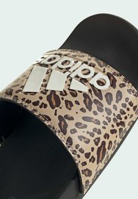 Sandały wsuwane w panterkę z czarną gumową podeszwą, z błyszczącym białym logo Adidas na pasku oraz teksturowanym czarnym wyłożeniem.