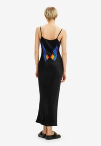 Abito maxi in satin nero con spalline sottili e stampa colorata delle ali di farfalla sulla schiena. Design lungo e aderente con fessure laterali.