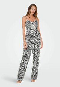 Mono en blanco y negro con un patrón de hojas, que cuenta con tirantes finos, una cintura ajustada y pantalones de pierna ancha. Textura de tela suave.