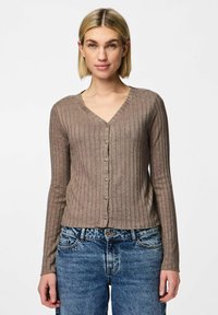 Brun ribbad cardigan med långa ärmar, V-ringning och knäppning, i kombination med denimjeans. Texturerad tyg, avslappnad passform.