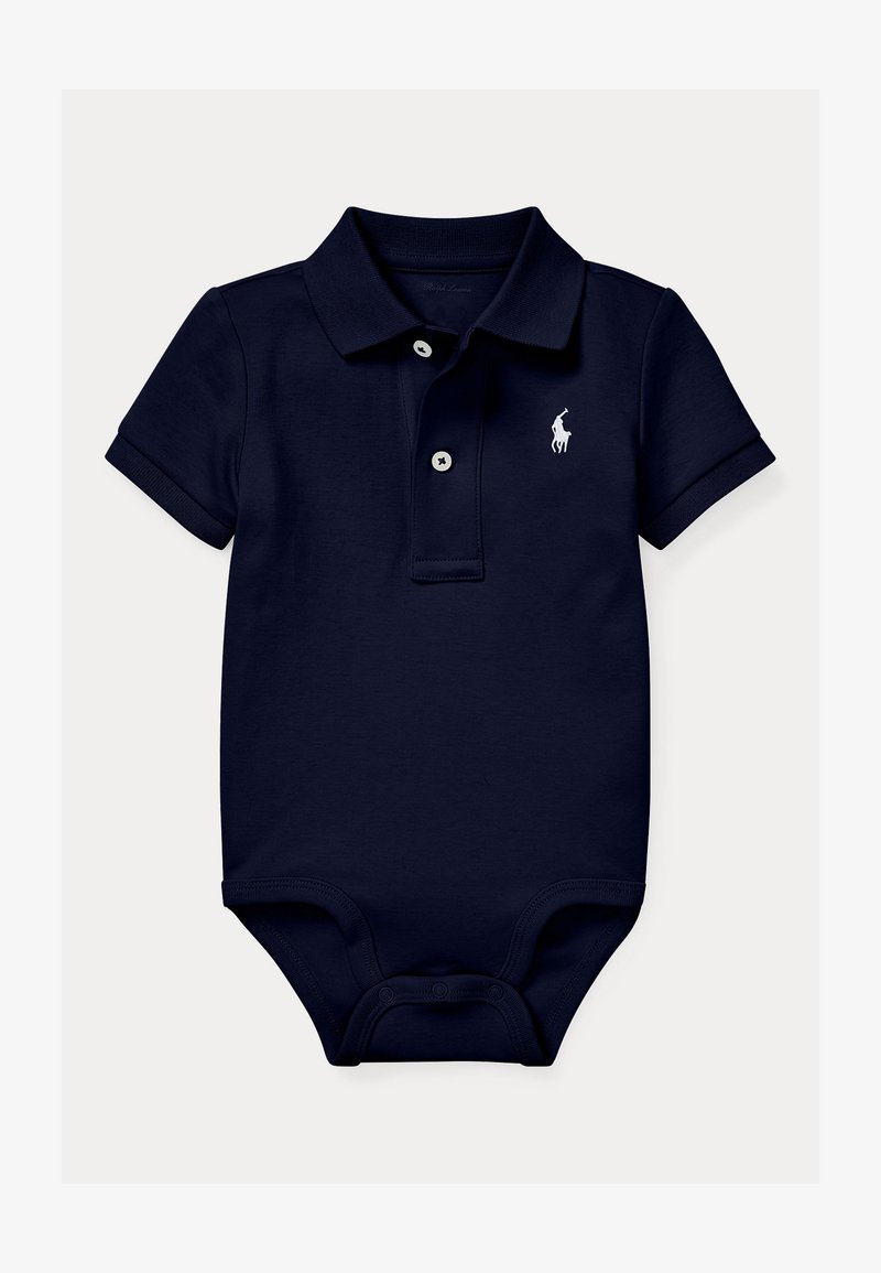 Βαμβακερό κορμάκι πόλο σε ναυτικό μπλε χρώμα με κοντά μανίκια, ρεβέρ με δύο κουμπιά και λευκό κεντητό λογότυπο στο αριστερό στήθος. Κλείνει με κουμπωτά κουμπιά στο κάτω μέρος.