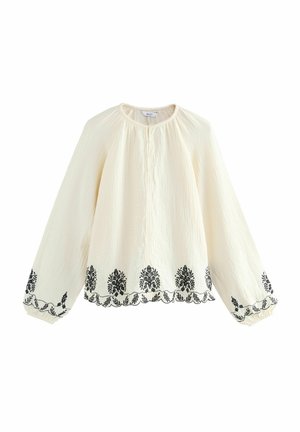 Hvid struktureret bluse med lange ærmer, prydet med sort blomsterbroderi langs kanten og ærmerne, samt en knaplukning ved halsen.