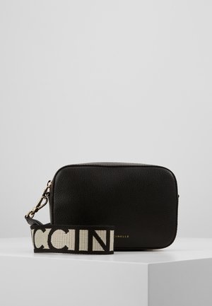 Sort tekstureret, rektangulær crossbody-taske med bred sort og hvid rem med kraftige bogstaver på en hvid overflade mod grå baggrund.