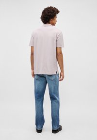 Ανοιχτό μοβ πουκάμισο πόλο με στενή εφαρμογή και κοντά μανίκια, συνδυασμένο με ανοιχτό μπλε τζιν ίσιου ποδιού που διαθέτει πίσω τσέπες.