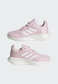 Scarpe sportive rosa con tomaia in rete traspirante, logo a tre strisce bianche, collo imbottito e suola spessa bianca. Design minimalista.