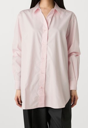 Camicia rosa con bottoni, dal taglio rilassato, maniche lunghe e colletto classico. Tessuto liscio con una lucentezza sottile e orlo dritto.
