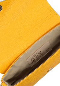 Borsa a tracolla gialla in pelle con una superficie testurizzata e un interno in tessuto beige, etichetta stampata con la dicitura "Made in Italy" e chiusura a scatto.
