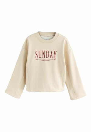 Light beige sweatshirt made of soft material, with a round neckline and boxy shape. Features red printed text "SUNDAY since 1982" on the front.