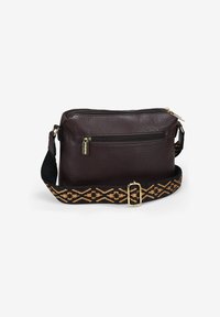 Bolso de crossbody de cuero marrón con superficie texturizada, cremallera dorada y correa de tela estampada en negro y dorado. Forma compacta y rectangular.