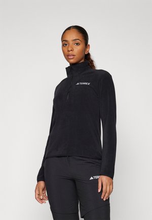 Sudadera de forro polar negro con cuello alto y media cremallera. Presenta el logo "TERREX" en blanco en el pecho. Textura suave, ajuste ceñido.