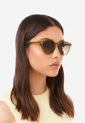 Kulaté sluneční brýle se zelenými obroučkami a hnědými čočkami se zabarvením od tmavšího k světlejšímu tónu. Design zahrnuje tenký rámeček a stylové prvky na stranicích.