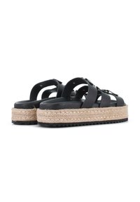 Sandalias de plataforma negras con suela de yute trenzado, con correas entrelazadas y herrajes en tono dorado. Superficie texturizada y suela de goma gruesa.