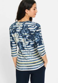 Bluse mit floralem Muster und blauen sowie cremefarbenen horizontalen Streifen, mit Dreiviertelärmeln und runden Ausschnitt. Weicher Stoff.