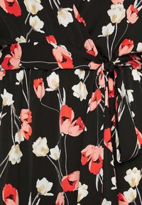 Robe en tissu noir ornée de motifs floraux rouges, roses et blancs. Comprend une ceinture à la taille et une texture fluide, avec des détails floraux délicats.
