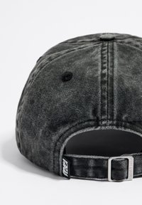 Cappello in denim nero con una finitura tessurizzata, dotato di un regolatore in metallo e di un'etichetta con logo sul cinturino. Dettagli cuciti sulla corona.