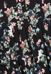 Tissu noir avec un imprimé floral dense en rose, blanc, bleu et vert, présentant des sections froncées créant un effet à étages.