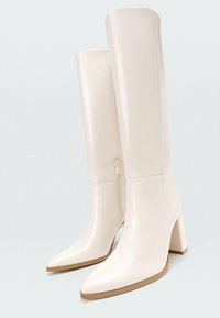 Knöchelhohe weiße Lederstiefel mit spitzer Zehenform, Blockabsatz und seitlichem Reißverschluss, die eine glatte Oberfläche und ein minimalistisches Design aufweisen.