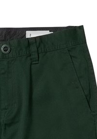 Donkergroene broek met een gladde textuur, voorzien van een knoopsluiting, riemlussen en zakken met een opening. Een maatlabel is zichtbaar aan de binnenkant van de tailleband.