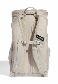 Zaino beige chiaro realizzato in tessuto texturizzato, con spallacci in rete, fibbie regolabili, maniglia superiore e un'etichetta con logo. Capacità di 20 litri.