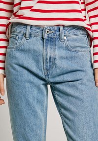 Light blue denim jeans featuring a high waist, five pockets, and a straight leg design. The fabric has a soft, slightly distressed texture.