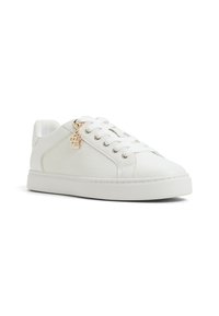 Weiße Leder-Sneaker mit strukturierten Einsätzen, Schnürdesign und einem kleinen goldenen Anhänger an der Seite. Flache Gummisohle.
