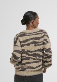 Béžin zebra-črte, puhast pulover z ohlapnim krojem, okroglim izrezom in rebrastim robom. Teksturirana, visokoh pileta tkanina z dolgimi rokavi.