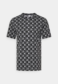 Lyhythihainen musta t-paita, jossa on valkoinen graafinen kuvio, joka kattaa koko paidan ja jossa on "K" ja "NIKE" -logot. Pyöreä pääntie, kevyt kangas.