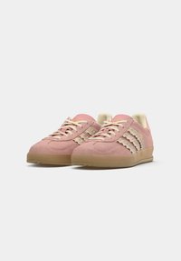 Roze suède sneakers met crèmekleurige accenten, gestructureerde veters en een lichtcrème interieur. Rubberen zool met een kleine hak.