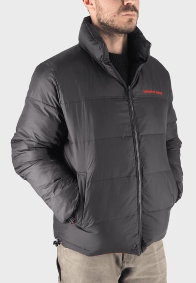 Giacca a vento nera con colletto alto, chiusura a zip frontale e due tasche laterali; presenta un testo logo rosso sul petto; materiale liscio e lucido.