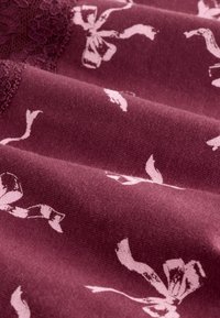 Tela burdeos con un acabado texturizado, que presenta un sutil patrón floral en rosa claro. Textura suave con delicados detalles de encaje.