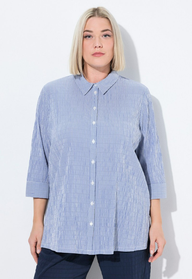 Camicia a righe blu e bianche con colletto e maniche a tre quarti, caratterizzata da una vestibilità rilassata e una texture liscia.