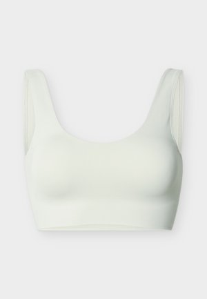 Sømløs hvid sports-bh med brede stropper og rund halsudskæring, designet til komfort og støtte, vist på en ensfarvet baggrund.