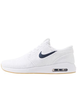 Biały sneaker Nike Air Max z granatowym logo Swoosh, dzianinową cholewką, sznurowaniem, widoczną poduszką powietrzną w podeszwie oraz jasnobrązową podeszwą zewnętrzną.