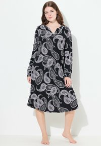 Mustapuku, jossa on valkoinen paisley-kuvio, pitkät hihat ja V-kaula-aukko. Valmistettu pehmeästä kankaasta, ulottuu polven alapuolelle.