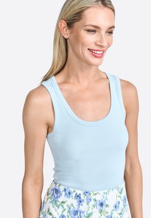 Light blue ribbed tank top with wide straps, paired with a floral skirt featuring blue and green patterns on a white background.