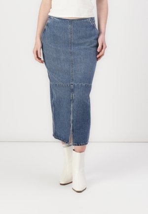 Denim midi skjørt i blått med en frontspalte, har en tettsittende midje og sidelommer. Kombinert med hvite ankelstøvler.