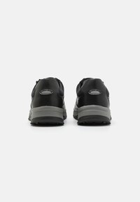 Schwarze Sportschuhe mit einem glatten Leder-Obermaterial und einer grauen Dämpfungssohle. An der Rückseite befindet sich ein Logo mit der Aufschrift "railingsoft". Strukturierte Grip-Laufsohle.