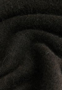 Ciemnobrązowy materiał o miękkiej, teksturowanej powierzchni; charakteryzuje się drobnymi włóknami i lekkim puszystym wykończeniem, co sugeruje ciepło i komfort.