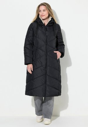Manteau long matelassé noir, avec capuche, fermeture éclair à l'avant et deux poches latérales. Texture lisse avec un motif de coutures en diagonale.