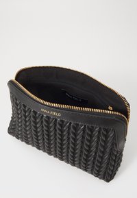 Clutch negro con cremallera hecho de material texturizado, que presenta un diseño trenzado y herrajes dorados. El interior incluye un bolsillo con cremallera y etiqueta de la marca.