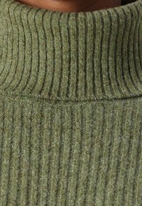 Πράσινο ριγέ ζιβάγκο φούτερ φτιαγμένο από υφάσματος με υφή, διαθέτοντας κατακόρυφες ρίγες και ψηλό γιακά για επιπλέον ζέστη.